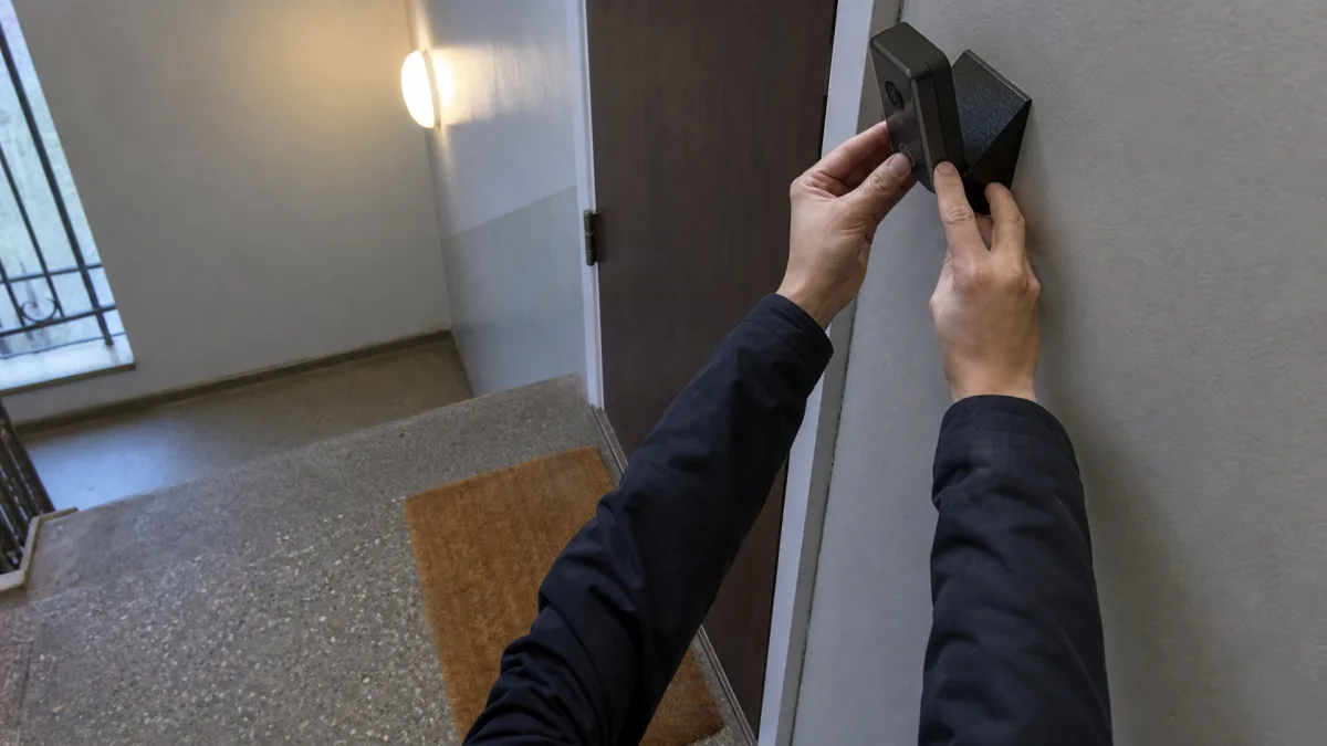 Boende vinklar en kameradörrklocka ned mot den egna dörrmattan i ett gemensamt trapphus